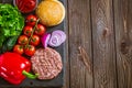 Top down view of ingredients for classic beef burger on stone board. Wooden table. Space for text Royalty Free Stock Photo