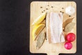 Top view on ingredients for diet dish from seafood. Fish pollock, fresh radish, slice lemon and garlic with spice on dark backgrou Royalty Free Stock Photo