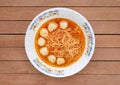 Top view instant noodles with meat balls in ceramic bowl against wooden plank