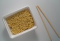 TOP VIEW: Instant noodles in a plastic dish with chopsticks on a white table