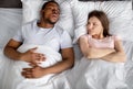 Top view of irritated young woman annoyed by her black husband snoring in bed Royalty Free Stock Photo