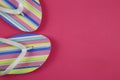 Top view on isolated colorful striped pair flip flops on pink background with copy space