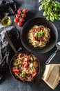 Top of view italian pasta spaghetti bolognese in plate and pan with tomatoes and basil