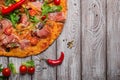 Top view of italian pizza on a rustic table background. A piece of salami pizza with cherry tomatoes and hot chili