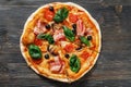 Top view of Italian rustic PIZZA with mushrooms, basil, tomato, olives and cheese. Cut off a piece and pushed. Dark wooden table Royalty Free Stock Photo