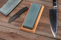 Top view on a jackknife, chef`s knife and whetstones on rustic wooden background