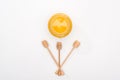 Top view of jar with honey and wooden honey dippers on white background.