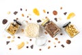 Top view of jars full of oats and various crunchy granola with ingredients scattered around - dried fruits, nuts and chocolate bar Royalty Free Stock Photo