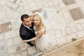 Top view of joyful wedding couple standing on pavement, looking at camera. Young woman bride embracing with groom. Royalty Free Stock Photo