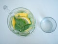 Top view on jug of homemade lemonade with mint leaves and lemon slices or lime wedges and glass cup Royalty Free Stock Photo