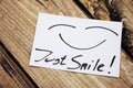 Top view of Just Smile sticky note on the wooden desk with smile face. Royalty Free Stock Photo