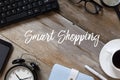 Top view of keyboard,glasses,magnifying glass,coffee,pen,notebook,clock, and smartphone on wooden background written with Smart