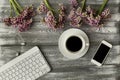 Top view of a keyboard, headphones and a cup of coffee, phone and a purple flower on a gray wooden table. Flat design.