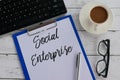 Top view of keyboard,pen,glasses,coffee,clipboard and paper written with Social Enterprise. Business and finance concept.