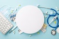 Top view keyboard, stethoscope, masks, medication, thermometer laid out on a serene pastel blue setting Royalty Free Stock Photo