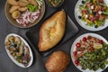 Top view of khachapuri dish with cheese and egg in Adjarian with Caesar and Greek salads with potatoes and herring Royalty Free Stock Photo