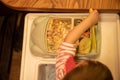 Top view, the kid sits in front of a children`s plate full of delicious mouth-watering food and takes a children`s plastic knife