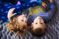Top view of kids laying in bed with gray cover. Little boy and girl, brother and sister, siblings play on the bed wearing matching Royalty Free Stock Photo