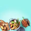 Top view of kitchen food waste collected in recycling compost pot. Peeled vegetables on chopping board, white compost bin on blue Royalty Free Stock Photo
