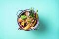 Top view of kitchen food waste collected in recycling compost pot. Peeled vegetables on chopping board, white compost bin on blue