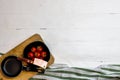 Top view of knife, small pan and fresh ripe cherry tomatoes in small black bowl on a rustic white wooden table. Ingredients and Royalty Free Stock Photo