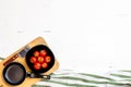 Top view of knife, small pan and fresh ripe cherry tomatoes in small black bowl on a rustic white wooden table. Ingredients and Royalty Free Stock Photo