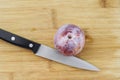 Top View of a Knife on a Wood Chopping Board with a Plum