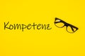 Top view of Kompetenz written on yellow background with glasses