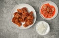 Top view Korean spicy deep-fried chicken topped white sesame with kimchi and pickled radish side dishes on the gray concrete table