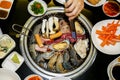 Top view of Korean style barbecue, assorted meat and seafood grilling over table top charcoal stove with various seasoning and Royalty Free Stock Photo