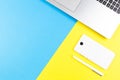 Top view of laptop computer, mobile phone and white pen on blue and yellow color background Royalty Free Stock Photo