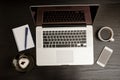 Top view of a laptop keyboard, coffee mug, a smartphone, a notebook and a dessert on a black wooden table Royalty Free Stock Photo