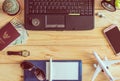 Top view of laptop, notebook, pen, sunglasses, passport, money,