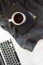 Top view of laptop, stacked notebook with a cup of coffee on top and cardigan jacket