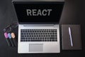 Top view of laptop with text React. React inscription on laptop screen and keyboard. Learn react language, computer courses,