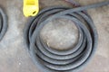 Top view of a large coil of black plastic hose laid on the ground in an industrial area.