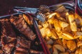 Top view, large dishes with a large number of fried potatoes and grilled steaks, appetizing food on a food court. background Royalty Free Stock Photo