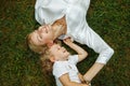 Top view of laughing family with closed eyes lying on grass in summer having fun. Young woman relaxing with little girl. Royalty Free Stock Photo