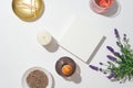 Top view of a lavender bouquet, a white podium, a bottle of essential oil diffuser, a candle, matches and dried lavender arranged