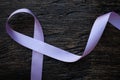 Top view of lavender or light purple orchid color ribbon on dark wooden background. General and testicular cancer and epilepsy. Royalty Free Stock Photo