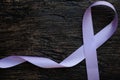 Top view of lavender or light purple orchid color ribbon on dark wooden background. General and testicular cancer and epilepsy. Royalty Free Stock Photo