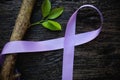 Top view of lavender or light purple orchid color ribbon with growing tree plant on dark wooden background. General and testicular Royalty Free Stock Photo