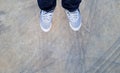 Top view of leg wearing blue jeans and gray or grey sneakers or fashion shoes on floor with car wheel or brake mark on road Royalty Free Stock Photo