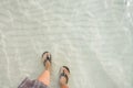 Top view legs in black flip flop underwater of sea on the beach with white wave sand. vacation summer in a holiday Royalty Free Stock Photo