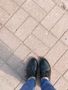 Top view of the legs shoes girls feet, women in patent shoes on the background of a stone concrete square paving rectangular tile