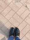 Top view of the legs shoes girls feet, women in patent shoes on the background of a stone concrete square paving rectangular tile