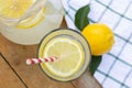 Top view of lemonade in a glass with a slice of lemon and a red and white straw on wooden table outdoors. Towel, lemon with leaf, Royalty Free Stock Photo