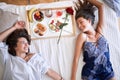 Top view of lesbians smiling, holding hands, having breakfast, lying on bed. lesbian, couple, breakfast in bed, romance concept Royalty Free Stock Photo