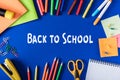 top view of lettering back to school from white paper surrounded by variety stationery on blue Royalty Free Stock Photo