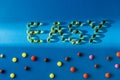 top view of lettering easy by pills near various tablets on blue background